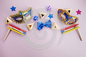 Purim celebration. Hamantashen or haman ears, noisemaker and mask on grey background. Top view