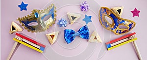 Purim celebration. Hamantashen or haman ears, noisemaker and mask on grey background. Top view