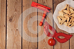 Purim holiday concept celebration with clown mask and hamantaschen cookies on wooden background.