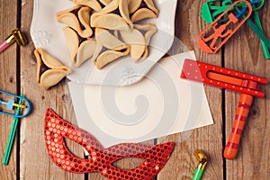 Purim holiday concept with greeting card and hamantaschen cookies on wooden background.