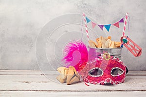 Purim holiday concept with hamantaschen cookies or hamans ears in bucket and carnival mask