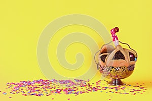 Purim holiday concept with hamantaschen cookies or hamans ears over yellow color background.