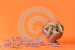 Purim holiday concept with hamantaschen cookies or hamans ears or ozney haman over colorful confetti background.