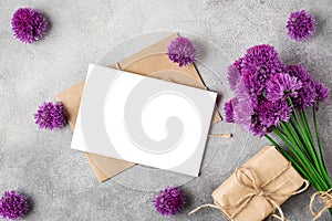 Purple alium flowers bouquet with blank greeting card and gift box on concrete background. top view. mock up. flat lay