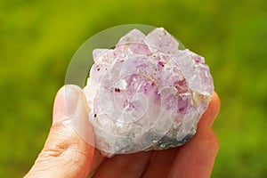 Purple amethyst gemstone from Brazil held in a hand
