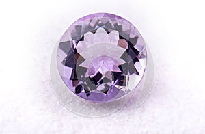 Purple amethyst gemstone jewelry on white sand.