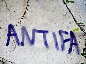 Purple ANTIFA Graffiti On Old White Wall