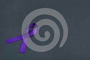 Purple awareness ribbon on black background, space for