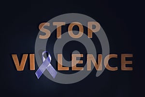 Purple awareness ribbon and phrase STOP VIOLENCE made of wooden letters on black background