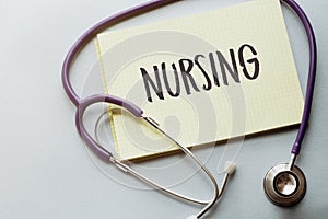 On a purple background a stethoscope with yellow list with text NURSING