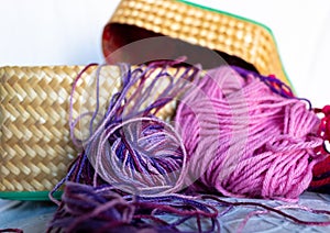 Purple balls wool in wicker basket and pink wool thread