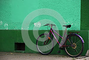 Purple bicycle near green wall