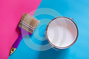 Purple brush with open can of white paint on blue and pink neon background. Trend concept
