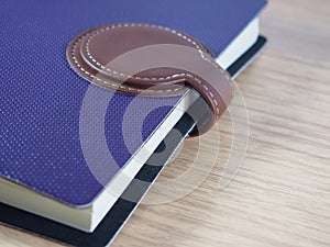 Purple business notebook with brown skin for closing on wood background