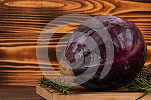 Purple cabbage and rosemary on cutting board, wooden background. Fresh vegetables, healthy organic food