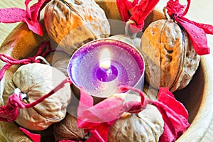 Purple candle with decorated wallnuts in a wooden bowl