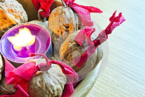 Purple candle with decorated wallnuts in a wooden bowl