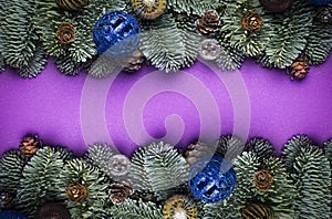 Purple Christmas background. Spruce twigs with New Year`s toys, cones
