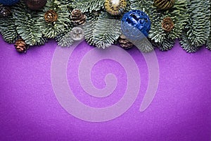 Purple Christmas background. Spruce twigs with New Year`s toys, cones