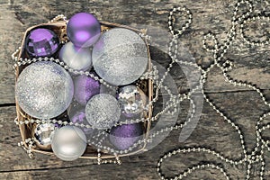 purple Christmas balls and silver, beads lie in a wooden basket