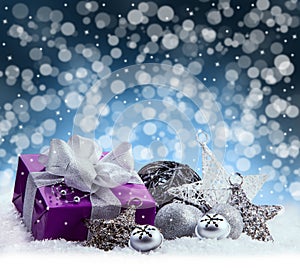 Purple Christmas package , gift of a silver ribbon. Jingle bells , silver christmas balls and christmas stars put on snow.