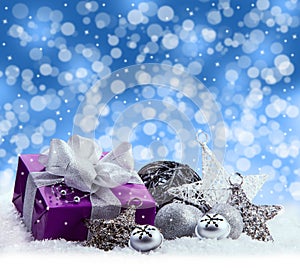 Purple Christmas package , gift of a silver ribbon. Jingle bells , silver christmas balls and christmas stars put on snow.