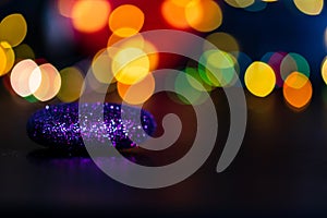 Purple Christmas tree ornament with colorful bokeh lights in the background