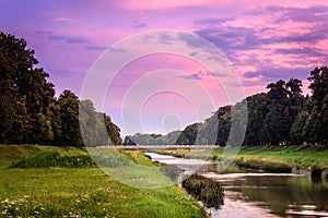 Purple, cloudy sunset sky over blurred motion Nisava river and Love bridge