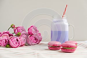 Purple coffee in stylized mason jar cup with macarons and roses and colorful decoration. Blueberry milk shake. Unicorn coffee.