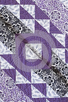 Purple coloured handmade patchwork bed quilt with various fabric geometric patterns