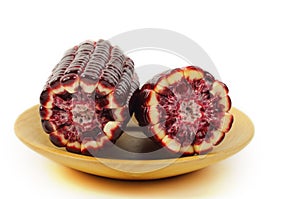Purple corn isolated on wooden plate.