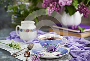 Purple cup of tae and lilac on gray background
