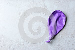 Purple deflated balloon on grey background