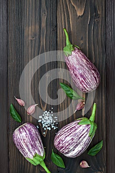 Purple eggplant, garlic and basil leaves from above on the old wooden board with free text space. Fresh harvest from the garden. T