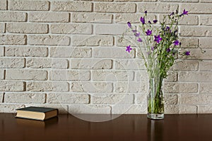 Purple flowers and book on a brick wall background