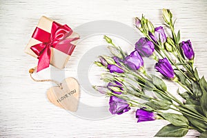 Purple flowers and box with a gift on a white background. Celebratory concept.