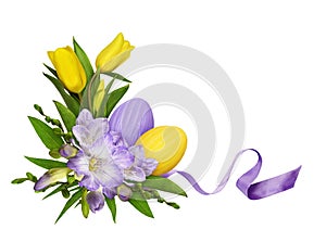 Purple freesia flowers and yellow tulips in a Easter corner floral arrangement with painted eggs isolated on white