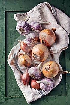 Purple garlic bulbs and onions on a linen towel