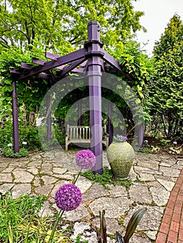 Purple gazebo structure with bench and purple flowers