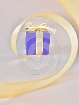 Purple gift box at the end of the spiral yellow ribbon, white background, vertical.