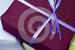 A purple gift box tied with a blue ribbon. Present for christmas, new year or birthday.