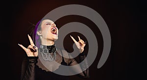 Purple hair goth woman screaming, halloween makeup and crazy expression dark background