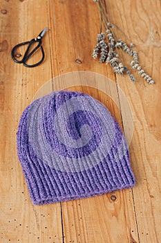 Purple handknitted hat on a wooden table