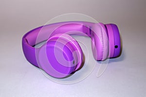 Purple headphones on a grey background.