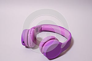 Purple headphones on a grey background.