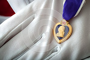 Purple Heart medal held with white gloves