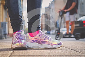 Purple holographic sneakers on a girl legs, with electric scooter in the background, selective focus