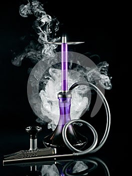 Purple hookah with a flask and tongs on a black background. Artistic shooting in a studio with white smoke and reflection