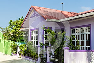 Purple house with white wooden windows under a red roof against a blue sky