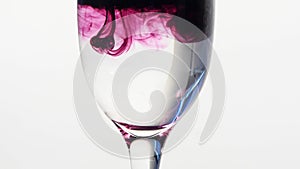 Purple ink dropping into glass of plain water